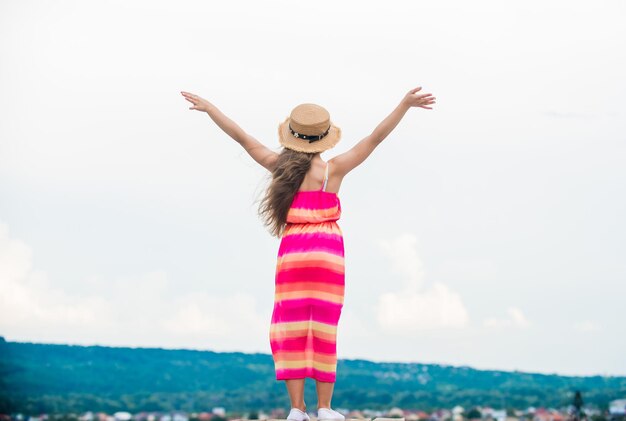 Felices vacaciones Linda chica en vestido de verano y sombrero al aire libre fondo del cielo Disfrutando de relajarse Niño niña pequeña feliz Libre y sin preocupaciones Buenas vibraciones Feliz día internacional de los niños Infancia feliz