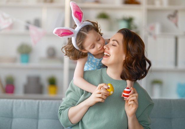 Felices vacaciones Madre e hija pintando huevos Familia celebrando Pascua