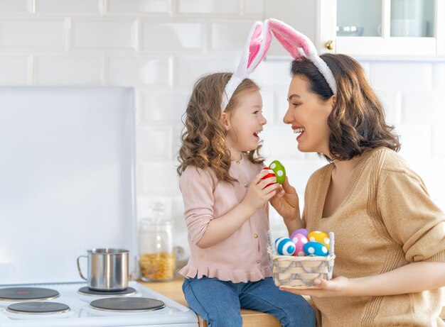 Felices vacaciones Una madre y su hija están pintando huevos Familia preparándose para la Pascua