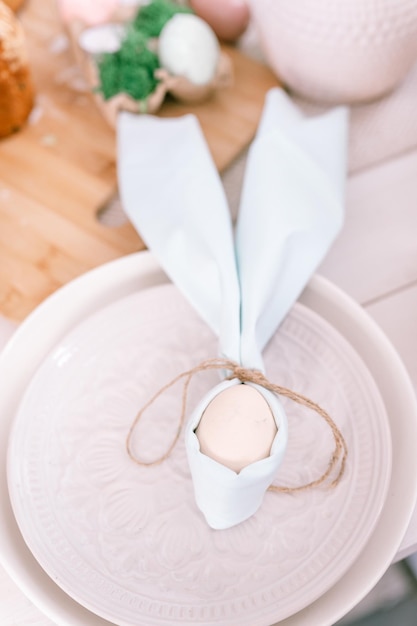 Foto felices vacaciones de pascua en la temporada de primavera decoración festiva del hogar comida tradicional huevo de gallina beige blanco envuelto en un paño azul pálido como orejas de conejo o conejo en un plato sobre la mesa