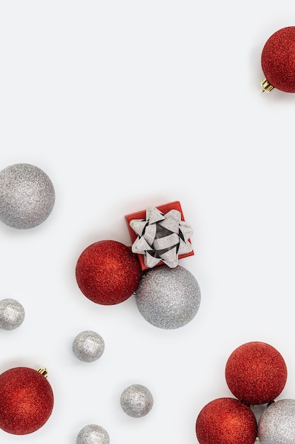 Felices vacaciones Patrón brillante con bolas de Navidad rojas y plateadas brillantes y una pequeña caja de regalo en blanco