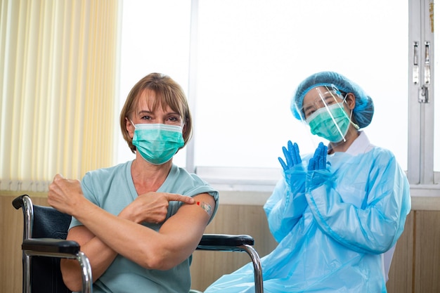 Foto felicidad de adultos mayores después de recibir la vacuna para prevenir el virus de la corona en el hospital. el personal médico sonríe con los pacientes en la sala de la clínica.