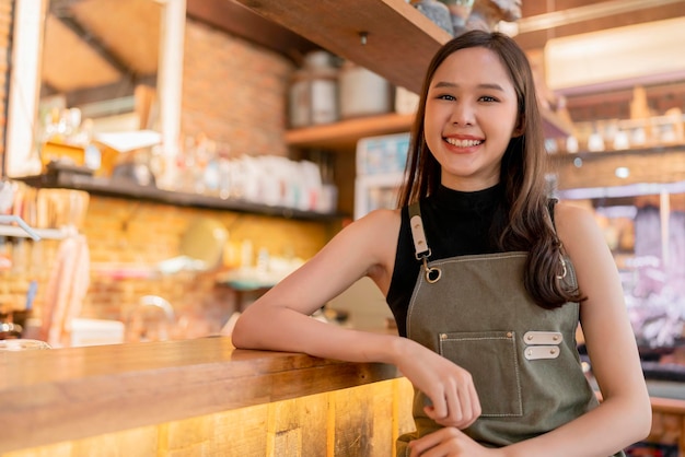 Felicidad alegre mujer asiática en uniforme pequeña empresa cafetería asia mujer propietaria que trabaja en cafetería mujer china barista haciendo café con máquina de café en la tienda de café