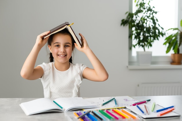 Felicidad dentro de mí. Hermosa niña alerta de ojos oscuros y cabello oscuro sonriendo y escribiendo en su cuaderno.