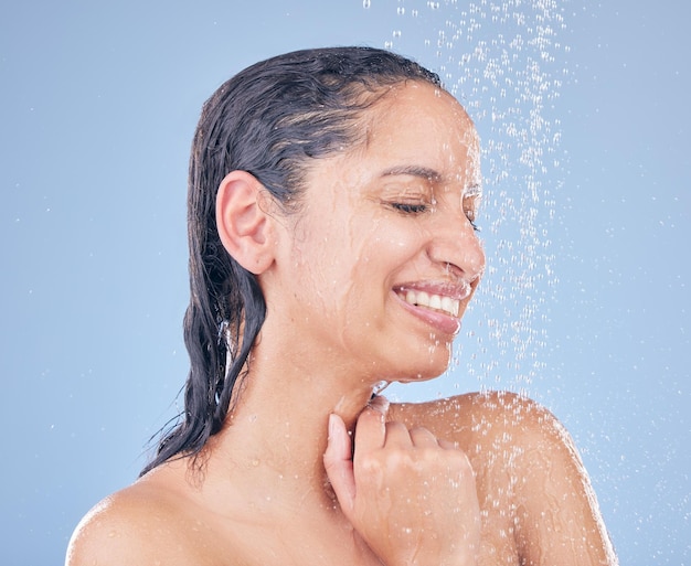 La felicidad está a solo una ducha de distancia Foto de una hermosa joven tomando una ducha contra un fondo azul