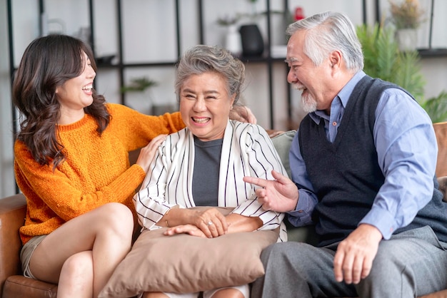 Felicidad familia asiática sincera de hija abrazo abuelo madre más anciano anciano acogedor relajarse en el sofá sofá sorpresa visitando en la sala de estar en casa juntos abrazar alegre familia asiática en casa