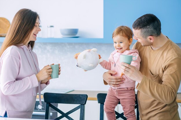 Felicidad familiar Los padres alegres pasan tiempo con su adorable hija en la cocina vieron algo y señalaron con los dedos