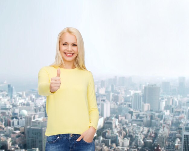 felicidad, gesto y concepto de la gente - mujer joven sonriente con ropa informal mostrando los pulgares hacia arriba