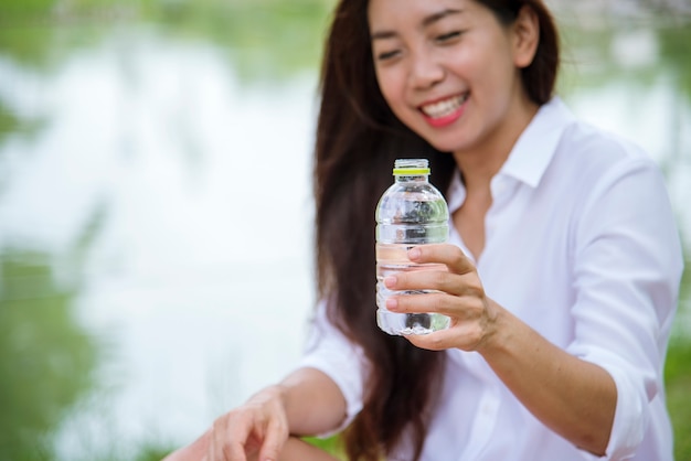 Felicidad Hermosas mujeres asiáticas chinas sosteniendo una botella de agua mineral feliz y sonriente