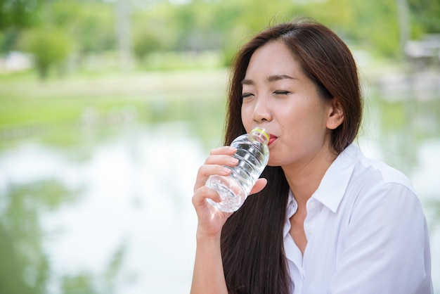 Felicidad Hermosas mujeres asiáticas chinas sosteniendo una botella de agua mineral feliz y sonriente