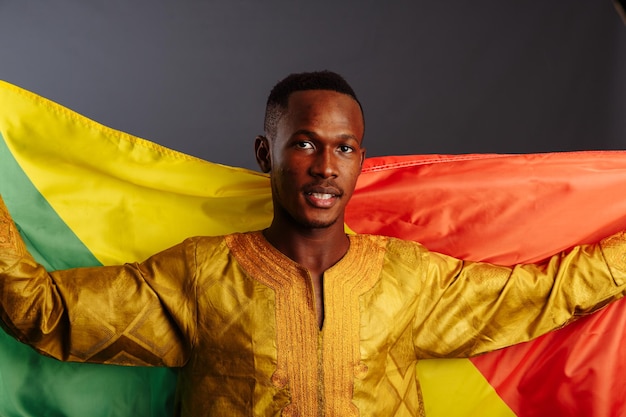 Felicidad hombre africano en ropa tradicional bailando con la bandera del Congo aislado sobre fondo gris