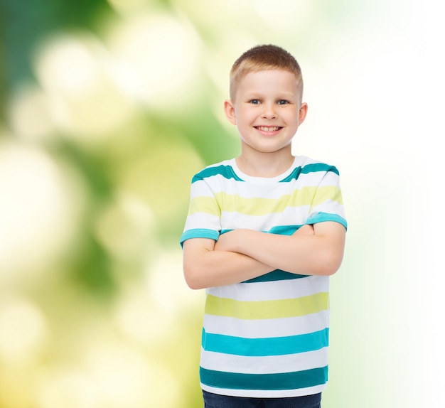 la felicidad, la infancia, la ecología y el concepto de la gente - un niño sonriente vestido de forma informal con los brazos cruzados sobre el fondo verde