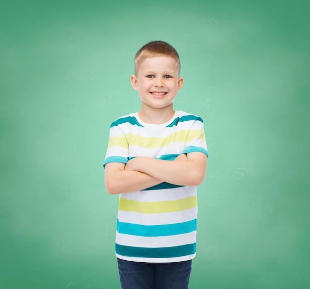 la felicidad, la infancia, la escuela, la educación y el concepto de la gente - un niño sonriente con ropa informal sobre el fondo de la pizarra verde