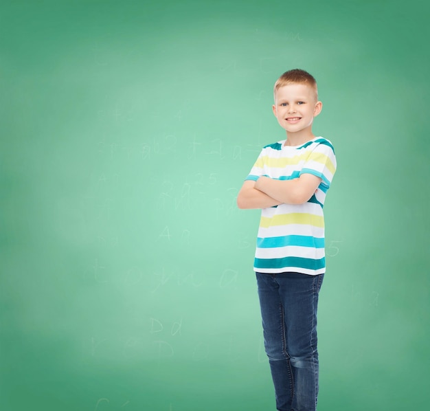 la felicidad, la infancia, la escuela, la educación y el concepto de la gente - un niño sonriente con ropa informal sobre el fondo de la pizarra verde