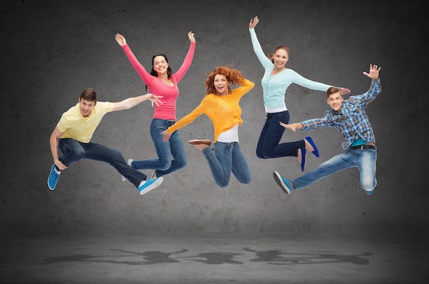 Foto felicidad, libertad, amistad, educación y concepto de la gente - grupo de adolescentes sonrientes saltando en el aire sobre fondo de tablero verde
