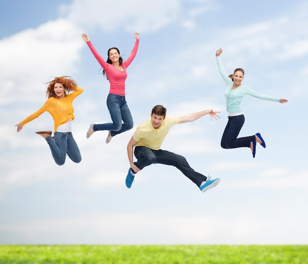 felicidad, libertad, amistad, movimiento, verano y concepto de personas - grupo de adolescentes sonrientes en el aire sobre el fondo natural