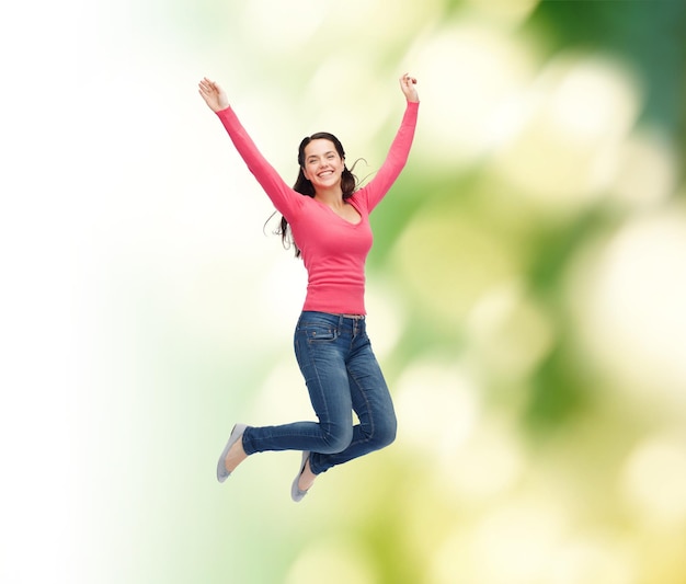 la felicidad, la libertad, la ecología y el concepto de la gente, una joven sonriente saltando al aire sobre un fondo verde