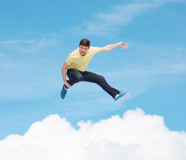 felicidad, libertad, movimiento y concepto de la gente - joven sonriente saltando en el aire sobre el cielo azul con fondo de nube blanca