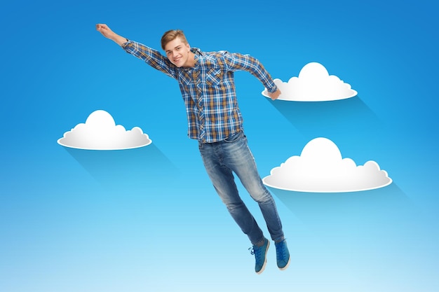 Foto felicidad, libertad, movimiento y concepto de la gente - joven sonriente volando en el aire sobre el cielo azul con fondo de nubes blancas