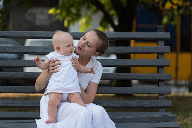 La felicidad de la maternidad. Joven madre abrazando a una linda hija sentada en un banco.