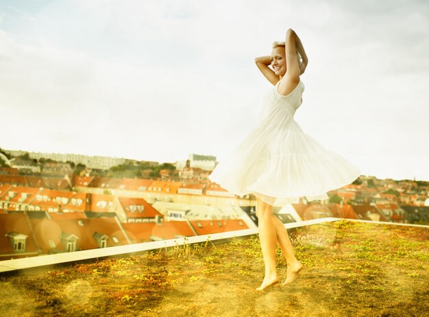 La felicidad no se puede comprar Hermosa mujer joven bailando en una azotea rodeada de bokeh