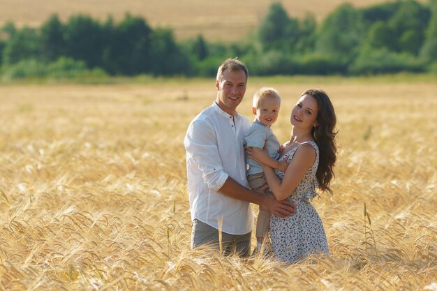 Felicidad de los padres, caminando por el campo con el niño. Madre, padre y niño pequeño ocios juntos al aire libre.