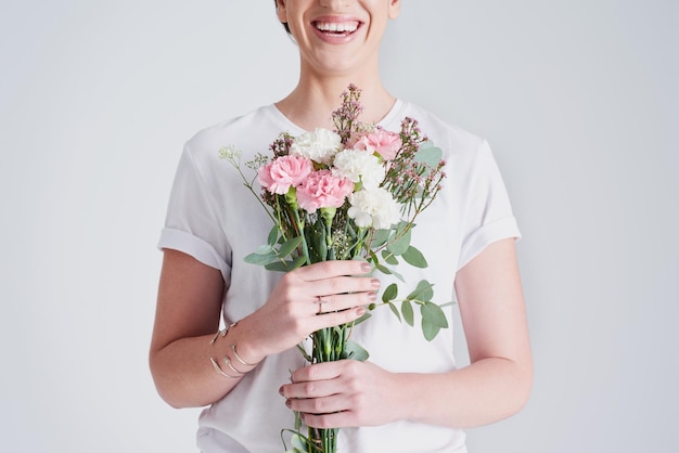 La felicidad proviene de las flores Foto de estudio de una mujer irreconocible sosteniendo un ramo de flores sobre un fondo gris