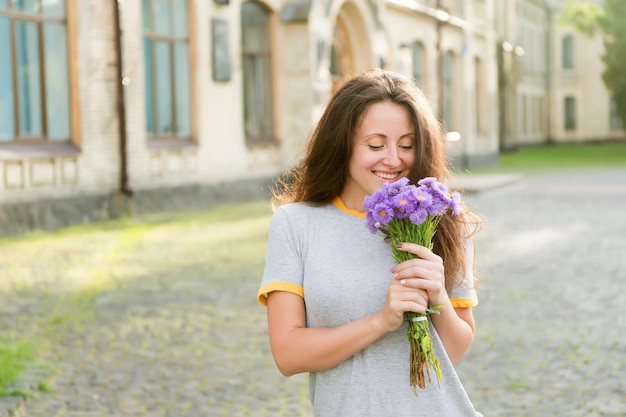 Felicidad simple. Placeres de verano. Hazla feliz. Entrega de flores. Flores silvestres frescas. Tienda de flores. Feliz día de la mujer. Niña sonriente mantenga ramo de flores. Concepto de saludos. Deleite y satisfacción.