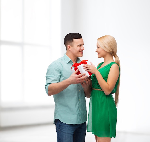 felicidad, vacaciones, celebración y concepto de pareja - pareja sonriente con caja de regalo