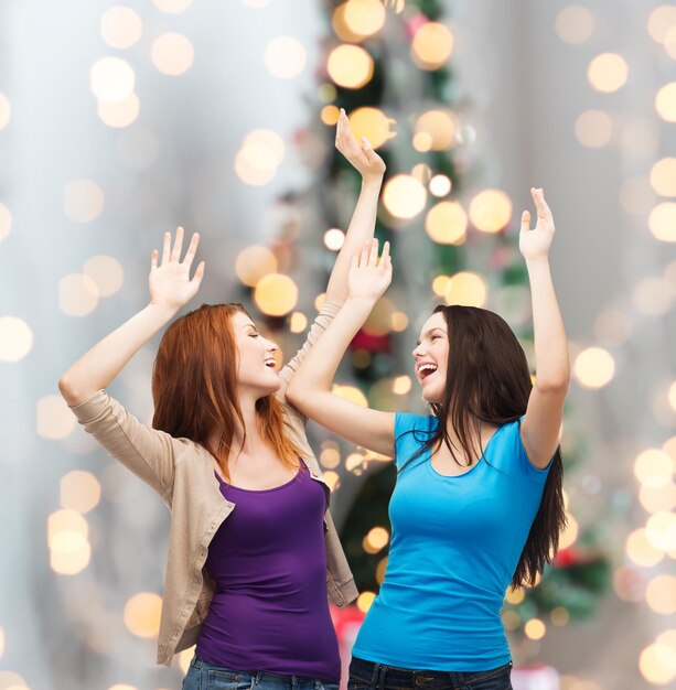 felicidad, vacaciones de invierno, amistad y concepto de la gente - adolescentes sonrientes divirtiéndose con el fondo del árbol de Navidad