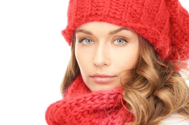 felicidad, vacaciones de invierno, navidad y concepto de la gente - cerca de una joven sonriente con sombrero rojo, bufanda y mitones sobre fondo blanco