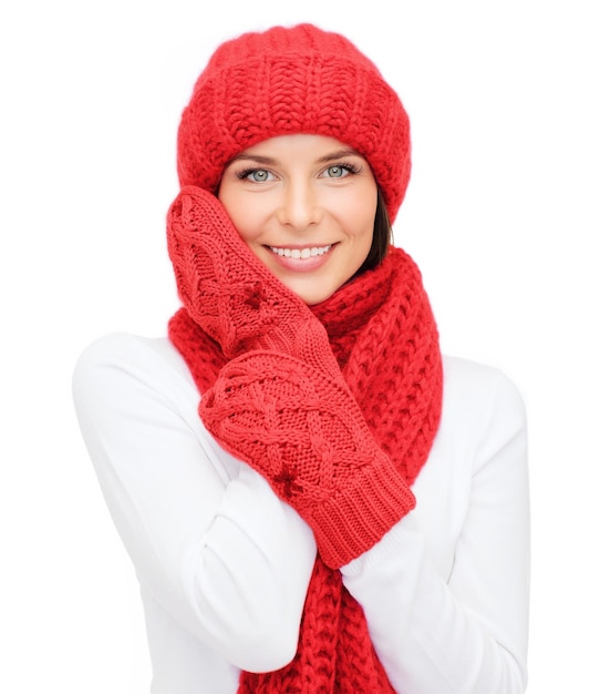 Foto felicidad, vacaciones de invierno, navidad y concepto de la gente - joven sonriente con sombrero rojo, bufanda y mitones sobre fondo blanco