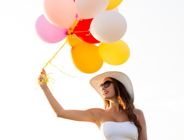 felicidad, verano, vacaciones y concepto de la gente - mujer joven sonriente con gafas de sol con globos al aire libre