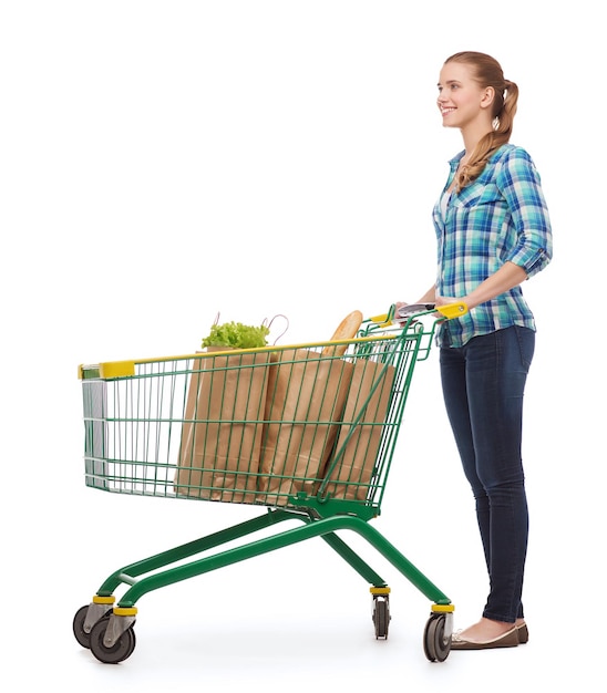 felicidade, compras e conceito de pessoas - jovem sorridente com carrinho de compras e comida nele