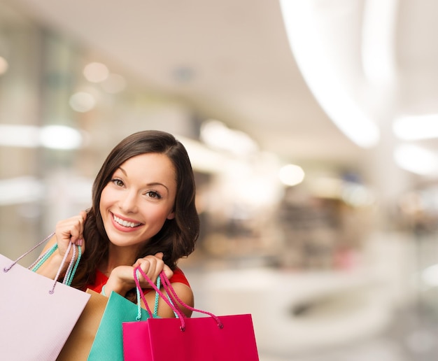 felicidade, consumismo, venda e conceito de pessoas - jovem sorridente com sacolas de compras sobre fundo de shopping