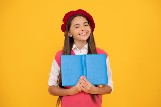 felicidade da infância. de volta à escola. garoto sonhador na boina pronta para estudar. livro de leitura de criança sorridente. estudante adolescente. aprender literatura. Educação. conto de fadas. feliz menina adolescente francesa segurar o caderno.