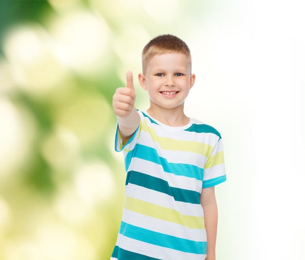 felicidade, infância, ecologia e conceito de pessoas - menino sorridente em roupas casuais, mostrando os polegares sobre fundo verde