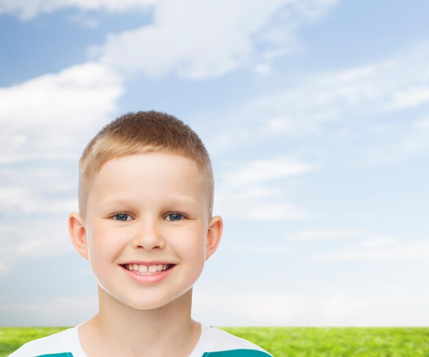 felicidade, infância, natureza e conceito de pessoas - menino sorridente sobre fundo natural azul