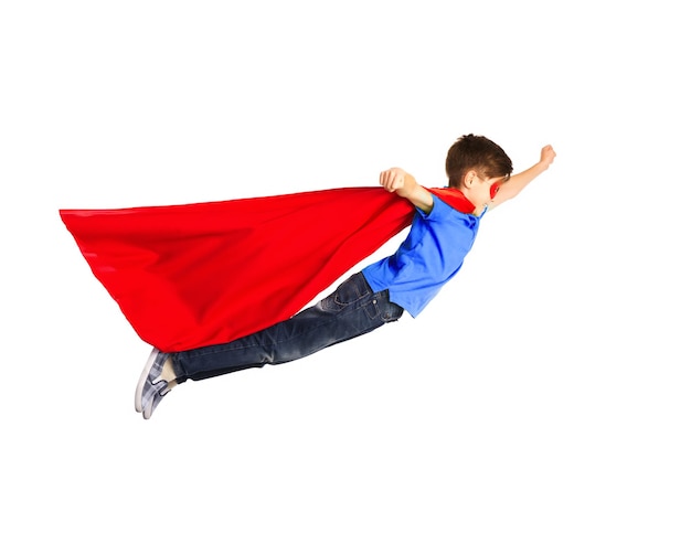 felicidade, liberdade, infância, movimento e conceito de pessoas - menino com capa vermelha de super-herói e máscara voando no ar