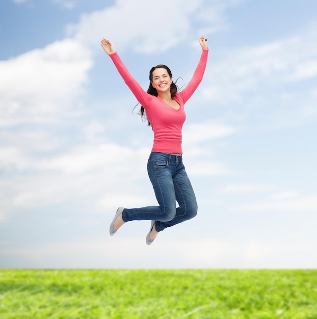 felicidade, liberdade, movimento, verão e conceito de pessoas - jovem sorridente pulando no ar sobre fundo natural