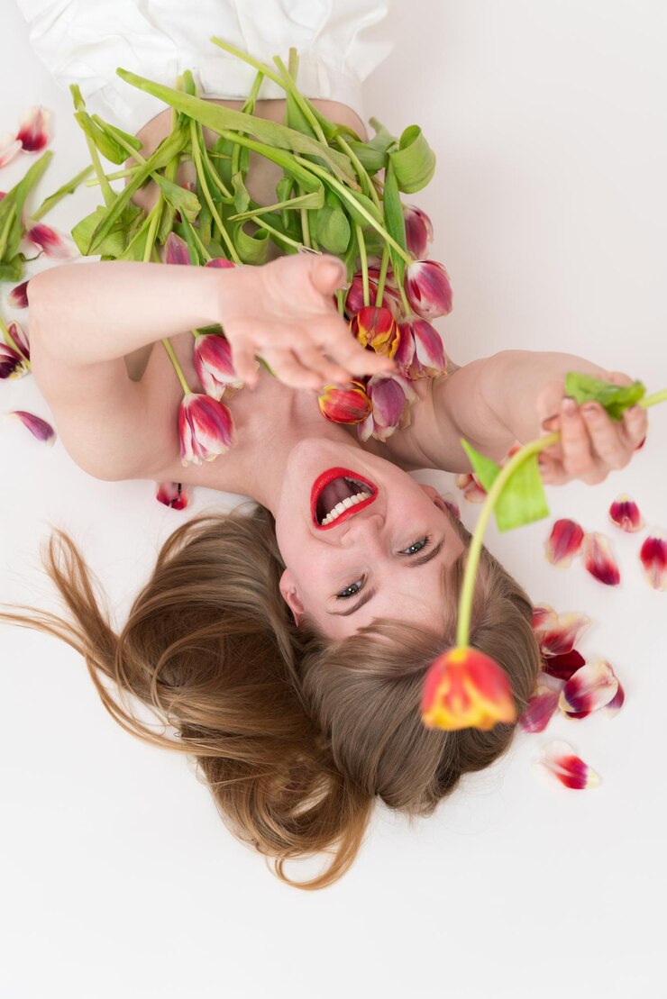 Felicidade mulher meio nua está posando com flores de tulipa para o dia da mulher em seu peito e em suas mãos