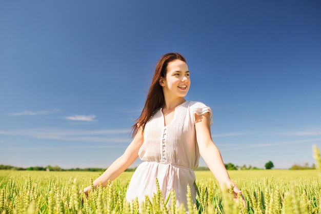 felicidade, natureza, verão, férias e conceito de pessoas - jovem sorridente no campo de cereais