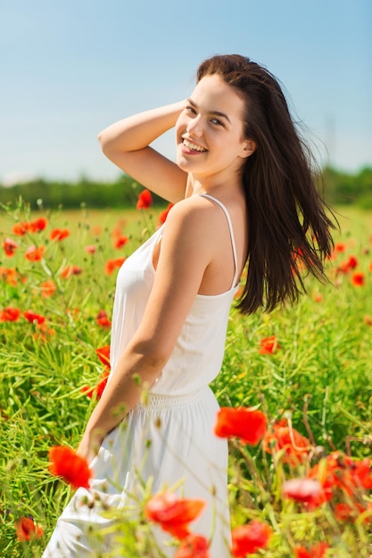 felicidade, natureza, verão, férias e conceito de pessoas - jovem sorridente no campo de papoulas