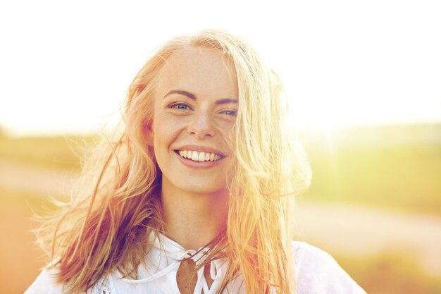 felicidade, país, férias de verão, férias e pessoas conceito - close de feliz sorridente jovem ou adolescente com cabelo selvagem ao ar livre