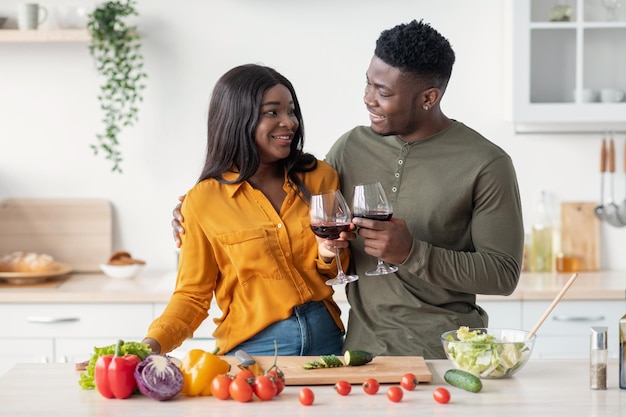 Felicidades para nós casal negro romântico bebendo vinho tinto na cozinha