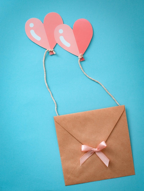 Felicitaciones por el día de San Valentín. Un sobre con un corazón volando sobre dos globos en forma de corazón es rosa.