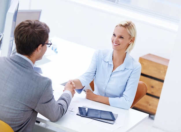 Felicitaciones, eres el mejor del equipo Foto de una mujer de negocios positiva que le da la mano a un miembro del personal masculino