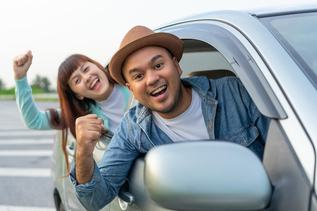 Feliz 2 jóvenes amigos conductor sonriendo mientras está sentado en un automóvil con la ventana delantera abierta Hombre y mujer asiáticos chreful a través de la ventana Pareja joven conduciendo automóvil para viajar en vacaciones