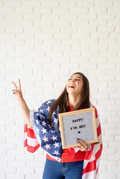 Foto feliz 4 de julho mulher com bandeira americana segurando cartaz com as palavras feliz 4 de julho