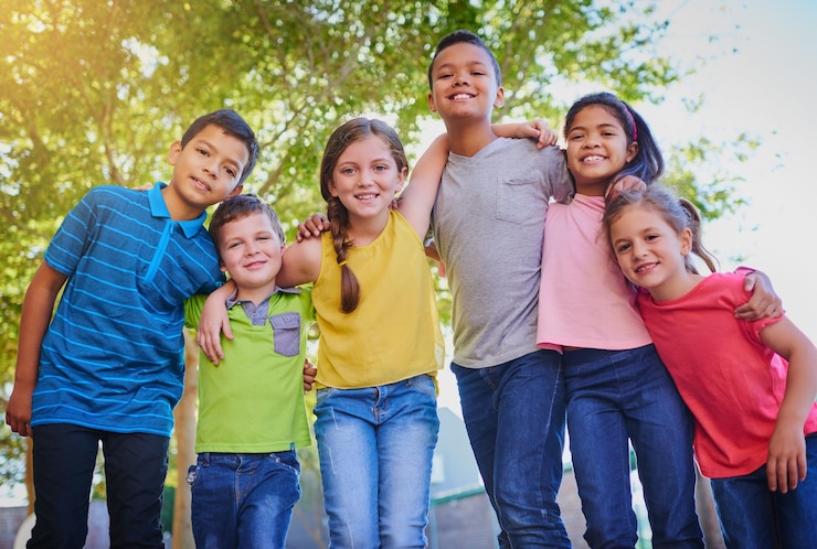 Foto feliz abrazo y retrato de niños en el parque para jugar unión y diversión juntos al aire libre diversidad juvenil y niños y niñas jóvenes en la naturaleza para la aventura infantil y la amistad en el patio de recreo